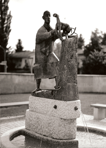 Guter-Hirte-Brunnen 1991, im Jahr der Errichtung; noch gibt es keinen Baumwuchs an der Einfriedungsmauer der Kirche St. Emmeram; mit freundlicher Genehmigung von Johannes Potzler.