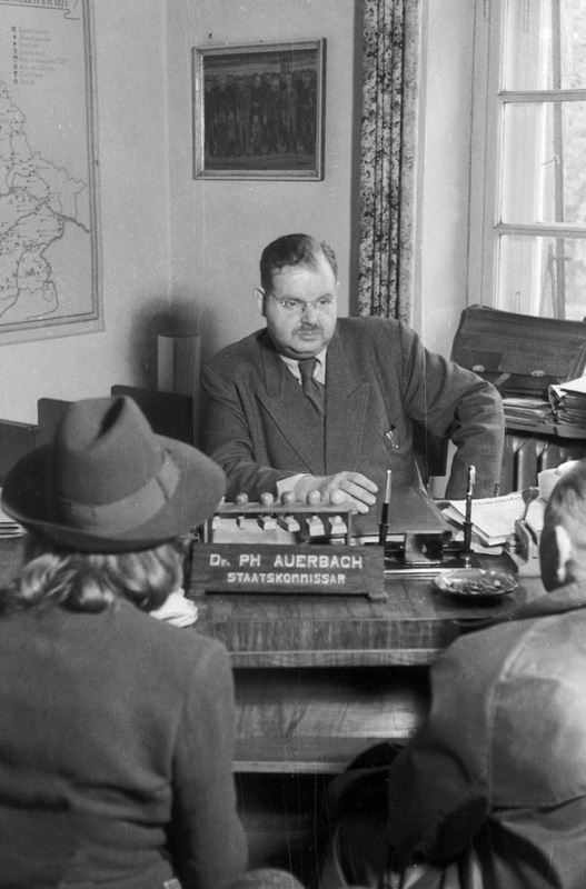 Philipp Auerbach mit zwei Klienten in seinem Büro in der Bogenhauser Holbeinstraße 11, 19.10.1948 (Ulla-Britta Vollhardt, Auerbach, Philipp, publiziert am 06.11.2023 in nsdoku.lexikon, URL: https://www.nsdoku.de/lexikon/artikel/auerbach-philipp-43)