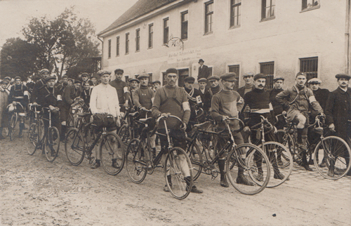 Radrennen vor der »Realen Gast- und Tafernwirtschaft Hans Sagmeister, Metzger und Wirt, Fremdenbetten« (Inschrift auf dem Gebäude), Eggenfeldener Straße 63, ca. 1914.