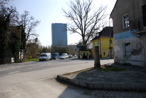 Kreuzung Eggenfeldener Straße / Friedrich-Eckart-Straße, 2015. hpt © Verein für Stadtteilkultur im Münchner Nordosten e.V. Links das ehemalige Gemeindehaus (gelbes Gebäude) und daneben der ehemalige der Schmied, gegenüber, am Bildrand rechts, der ehemalige »Alte Wirt« mit dem Kilometerstein, Eggenfeldener Straße 63.