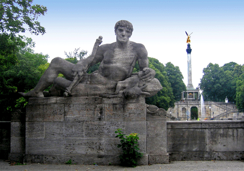 Die Jägerskulptur von Prof. Hermann Hahn an der Luitpoldbrücke in München im Jahr 2008, dahinter der Friedensengel mit der Anlage der Prinzregent-Luitpold-Terrasse. Die Skulptur wurde 1954 von Joseph Wackerle erneuert. © rufus46 / wikipedia commons