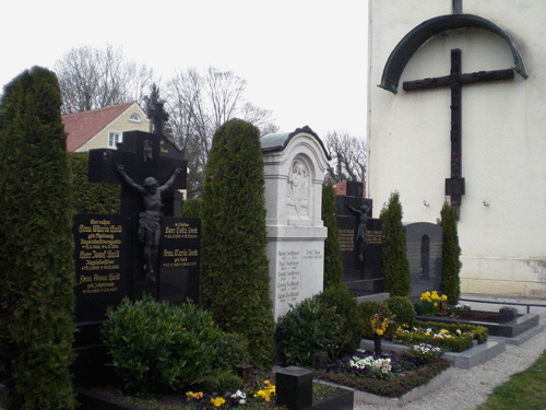 Blick auf die Familiengräber der "Loambarone" am Friedhof St. Lorenz, im Hintergrund das große Holzkreuz zum Gedächtnis an Rochus Dedler; © dietlind pedarnig, 2008
