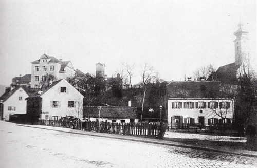 Kleinanwesen an der Montgelasstraße um 1890. Links im Hintergrund: die alte Bogenhauser Schule mit Feuerwehrturm, rechts außen: St. Georg. Buchscan aus: Karl, Willibald: Bogenhausen. Vom bäuerlichen Pfarrdorf zum noblen Stadtteil, München 1992.