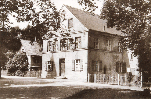 historische Aufnahme, die links den ehemaligen "Kreppenschneiderhof " (Muspillistraße 23) zeigt, den die Gemeinde Oberföhring 1910 erwirbt und in ein Schulnebenhaus umwandelt. Abgerissen nach 1970, steht heute hier ein Dienstgebäude mit Wohnung der Freiwilligen Feuerwehr Oberföhring, Muspillistraße 25.