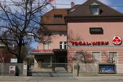 Das Togal-Werk von der Ismaninger Straße aus gesehen. Im Vorhof der St.-Georgi-Brunnen aus der ehemaligen »Betz'schen Gastwirtschaft«. Im Hintergrund das Haupthaus der ehemaligen Wirtschaft, das Gebäude rechts war die dazugehörige Metzgerei der Wirtschaft.© Verein für Stadtteilkultur im Münchner Nordosten e.V., 2008