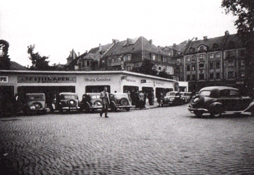 Gute Geschäfte und beginnenden Wohlstand signalisieren zahlreiche Autos vor den Behlefsläden Ecke Möhl-/Höchlstraße in der Nähe der »Devisenbörse« (ehemals Villa Winklhofer)